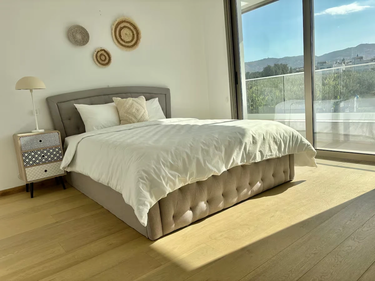 Helles Schlafzimmer mit Doppelbett und raumhohen Fenstern